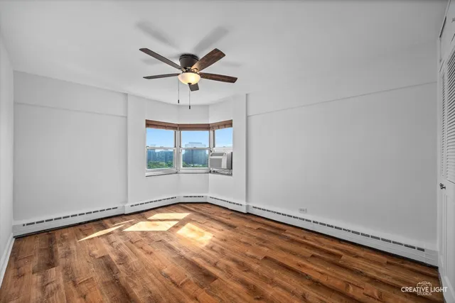 a view of empty room with wooden floor and fan