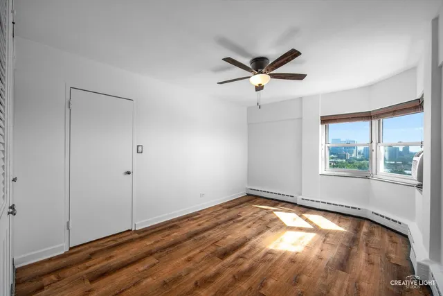 a view of empty room with wooden floor and fan