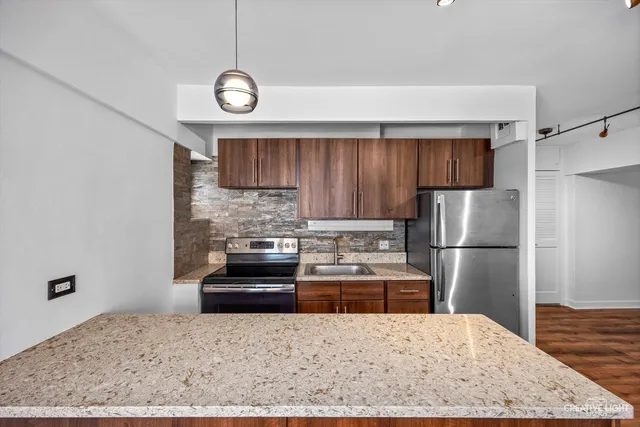 a kitchen with stainless steel appliances granite countertop a refrigerator a stove a sink and a stove