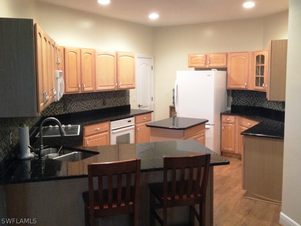 10220 Deal Road North Fort Myers, FL 33917 - Photo 7 of 21 a kitchen with granite countertop a stove a sink and a refrigerator
