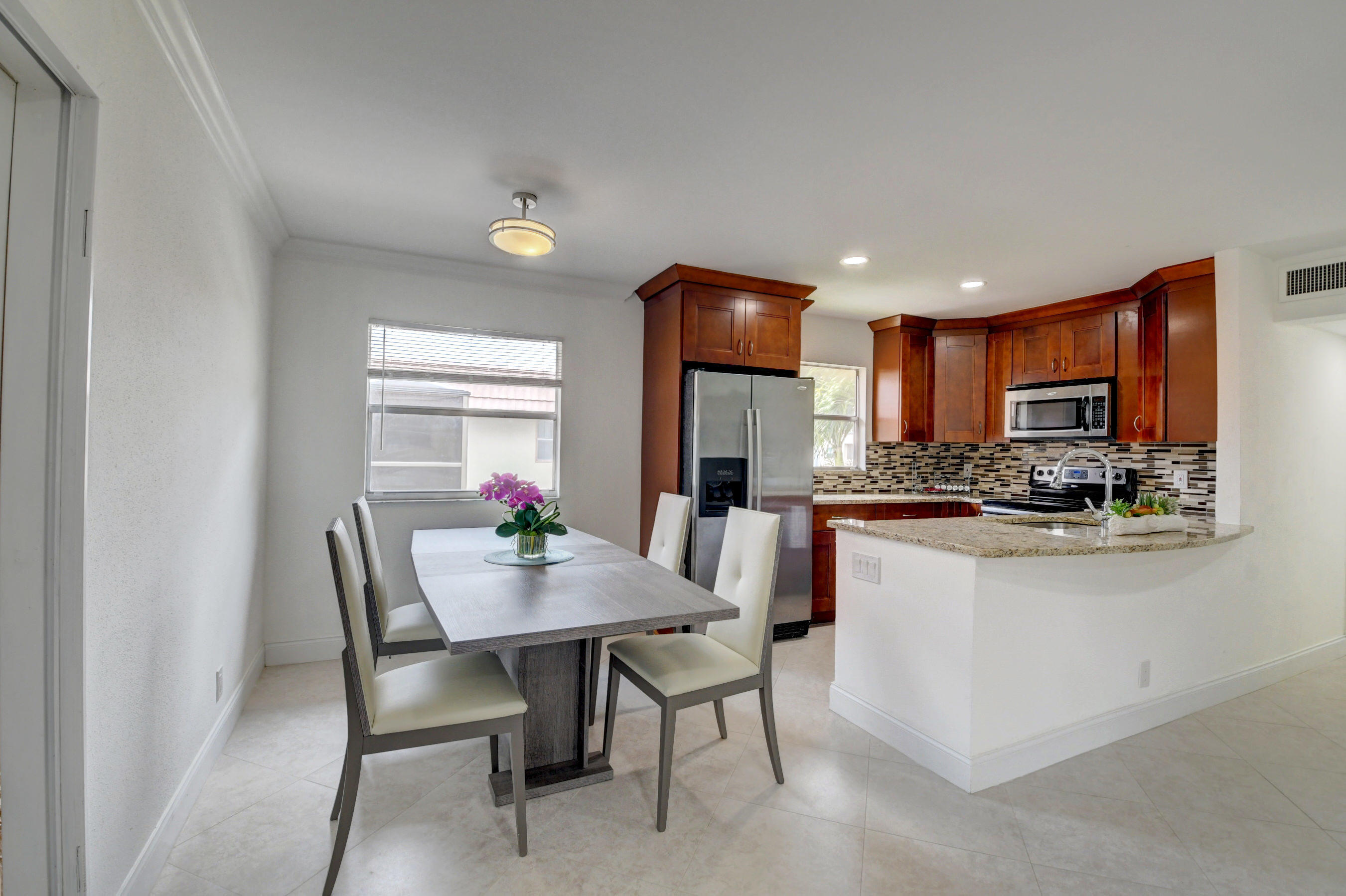 a kitchen with a dining table chairs and refrigerator