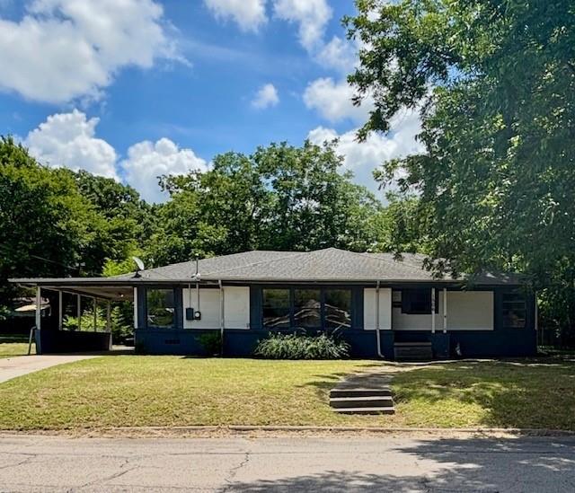 View of front of property featuring concrete driveway, an attached carport, and a front yard