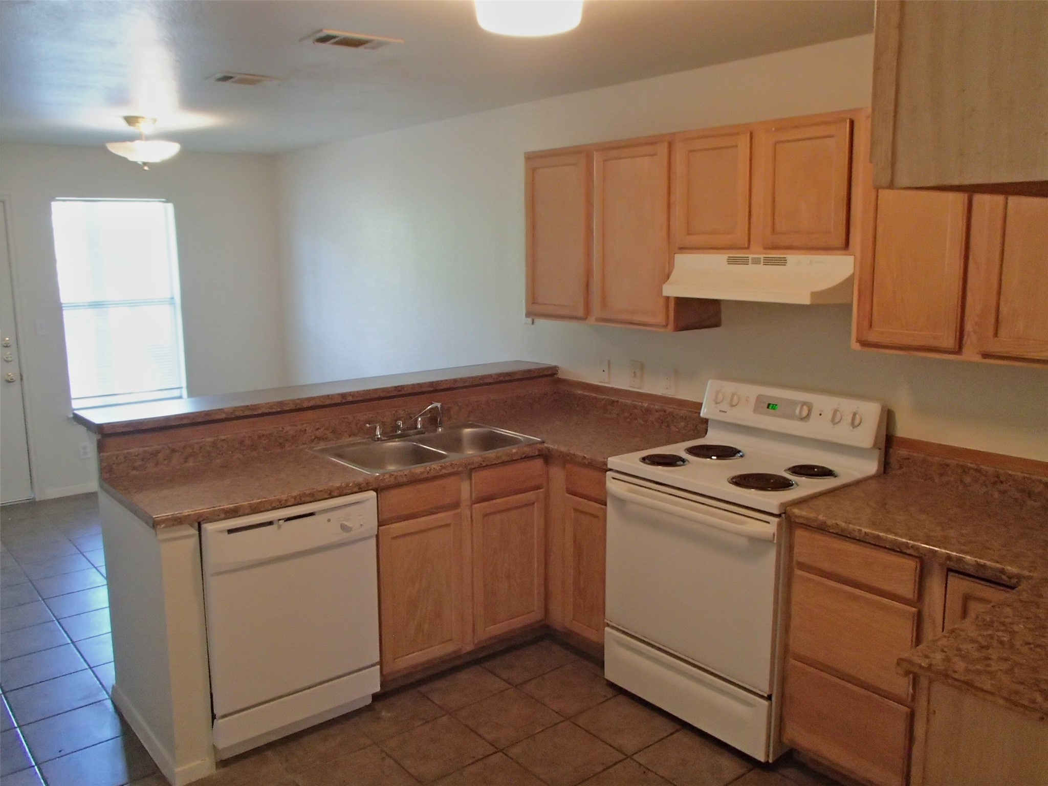 2202 Katy Lane, Unit A Georgetown, TX 78626 - Photo 3 of 9 Kitchen with light brown cabinets, a peninsula, and white appliances