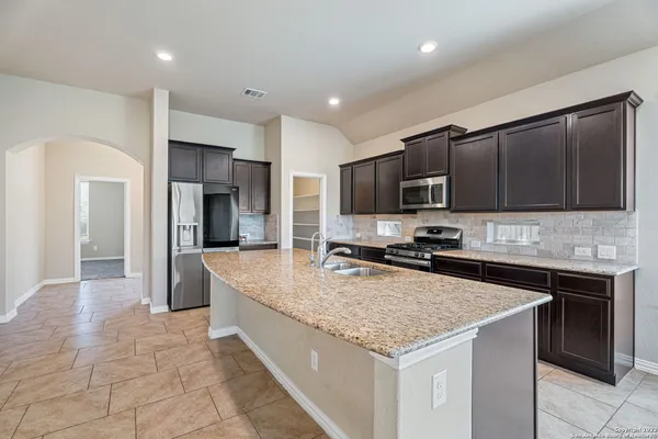 a kitchen with stainless steel appliances granite countertop a sink stove microwave and refrigerator