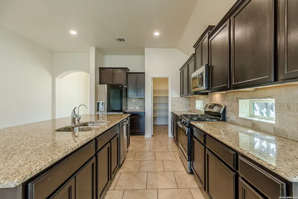 a kitchen with granite countertop stainless steel appliances a sink stove top oven and cabinets