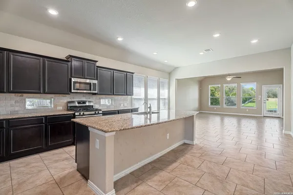 a large kitchen with stainless steel appliances granite countertop a stove sink and cabinets