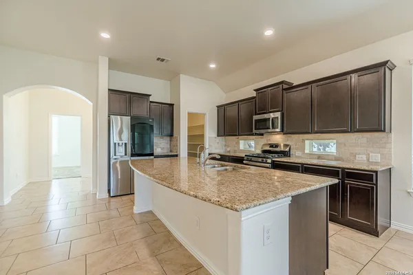 a kitchen with stainless steel appliances granite countertop a sink a stove top oven a refrigerator and dishwasher