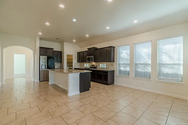 a large white kitchen with kitchen island granite countertop a large counter top stainless steel appliances and cabinets