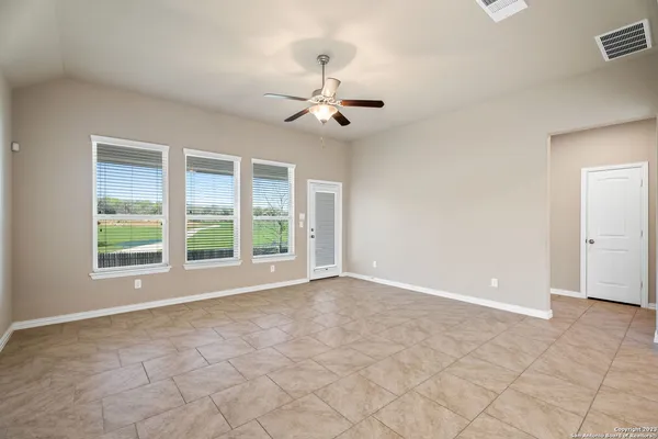 an empty room with windows and chandelier fan
