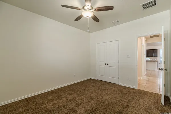 an empty room with closet and a chandelier fan