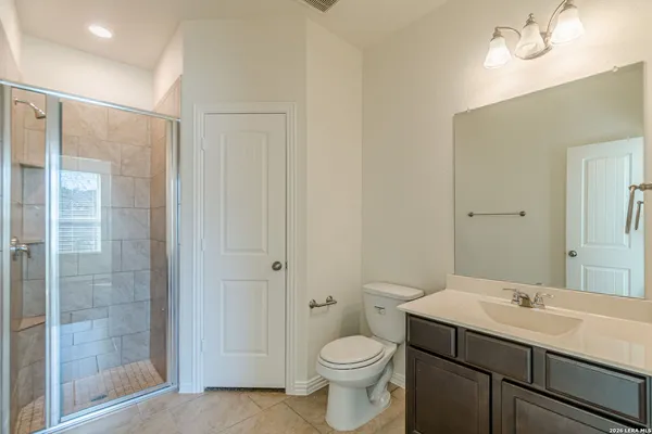a bathroom with a shower sink vanity mirror and toilet