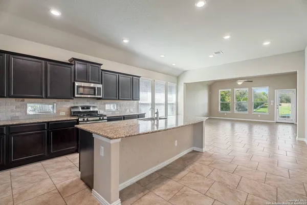 a large kitchen with stainless steel appliances granite countertop a stove sink and cabinets