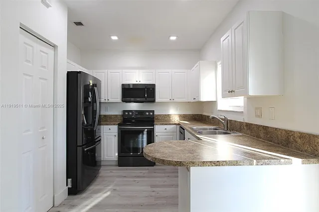 a kitchen with granite countertop a refrigerator stove and sink