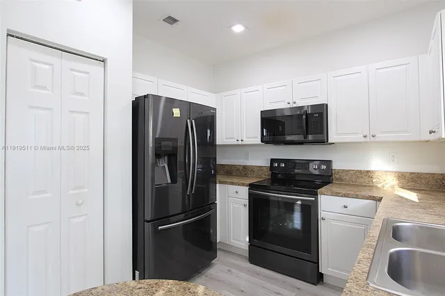 a kitchen with stainless steel appliances granite countertop a refrigerator stove and sink