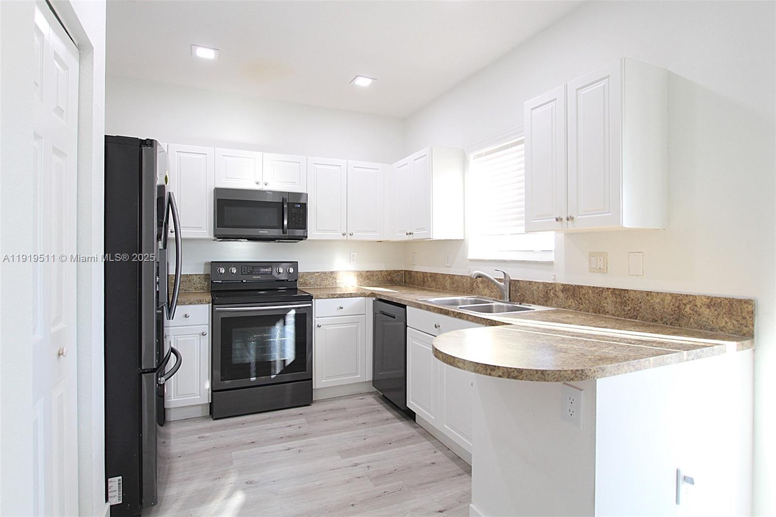 9390 Southwest 222nd Way, Unit 9390 Cutler Bay, FL 33190 - Photo 13 of 32 a kitchen with stainless steel appliances granite countertop a sink stove and refrigerator
