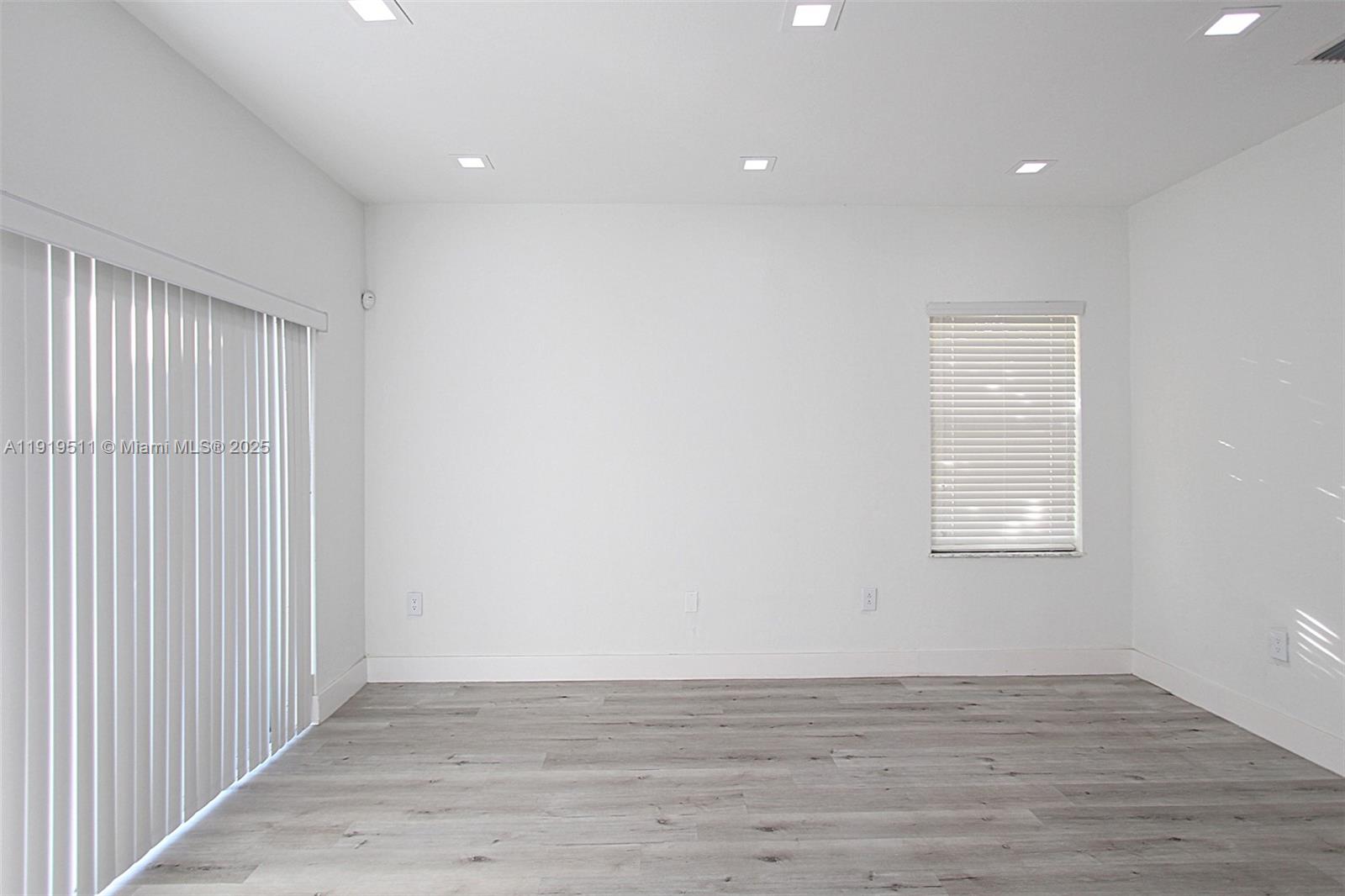 9390 Southwest 222nd Way, Unit 9390 Cutler Bay, FL 33190 - Photo 14 of 32 a view of an empty room with wooden floor and a window
