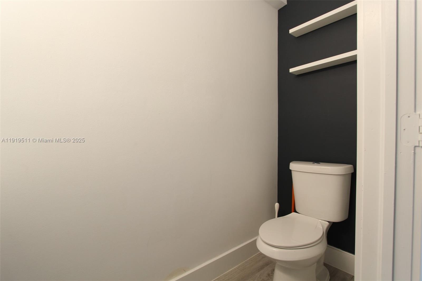 9390 Southwest 222nd Way, Unit 9390 Cutler Bay, FL 33190 - Photo 16 of 32 a white toilet sitting in a bathroom next to a wooden wall