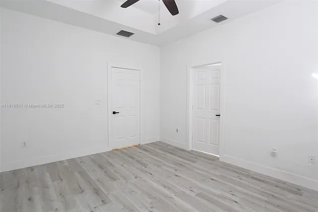 an empty room with wooden floor and ceiling fan