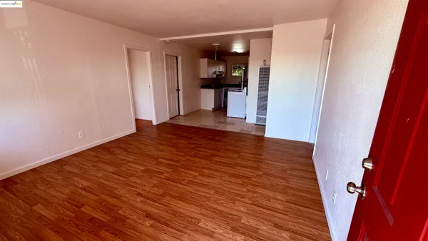 a view of a hallway view with wooden floor and a refrigerator