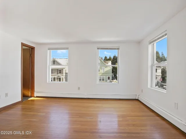an empty room with wooden floor and window