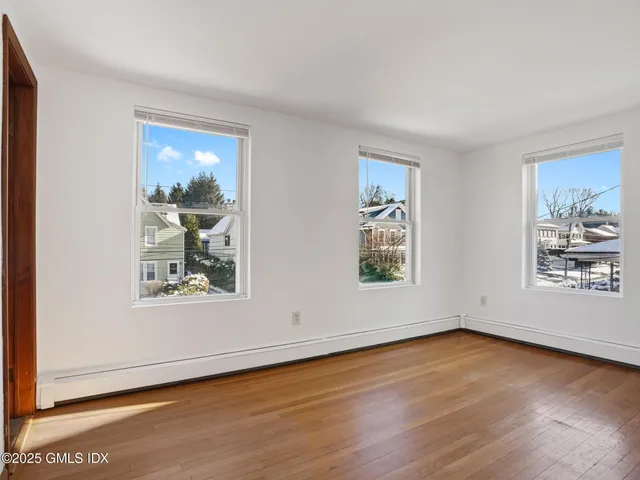 an empty room with wooden floor and windows