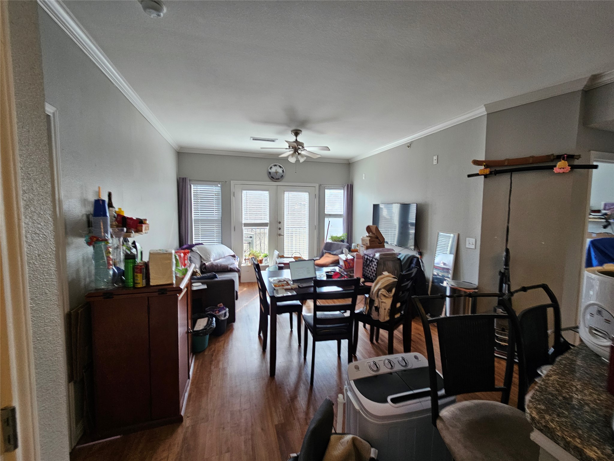 Dining area featuring dark wood-style floors, a ceiling fan, crown molding, and french doors