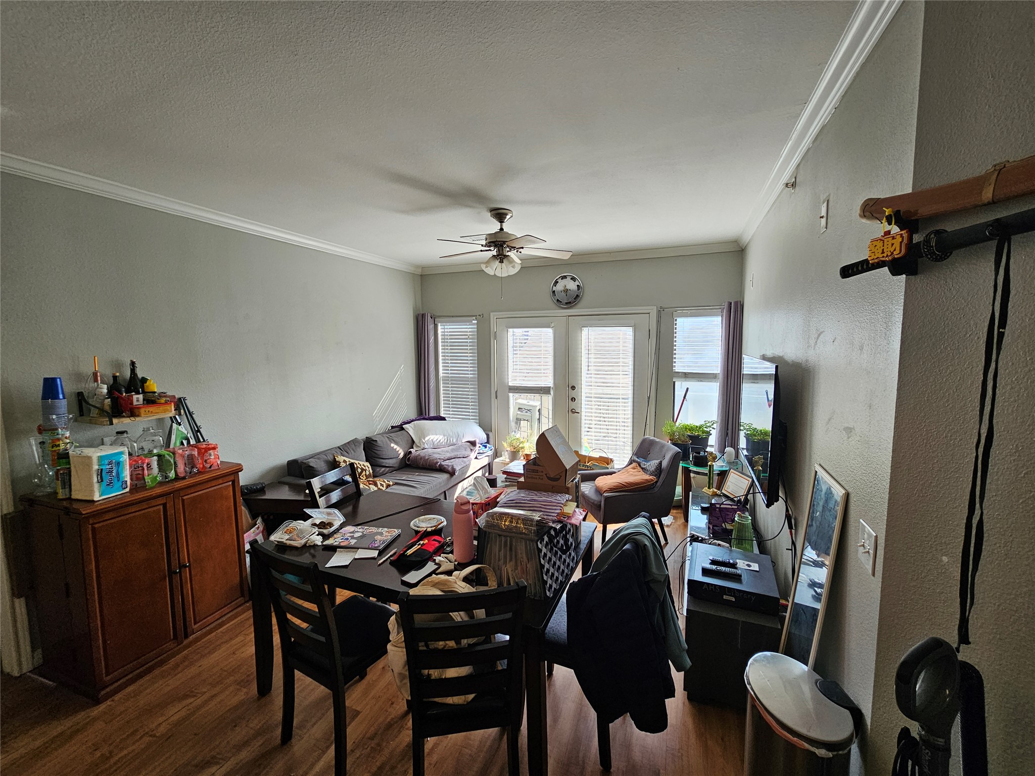 2502 Leon Street, Unit 304 Austin, TX 78705 - Photo 2 of 10 Living area featuring a ceiling fan, dark wood-type flooring, crown molding, french doors, and a textured wall