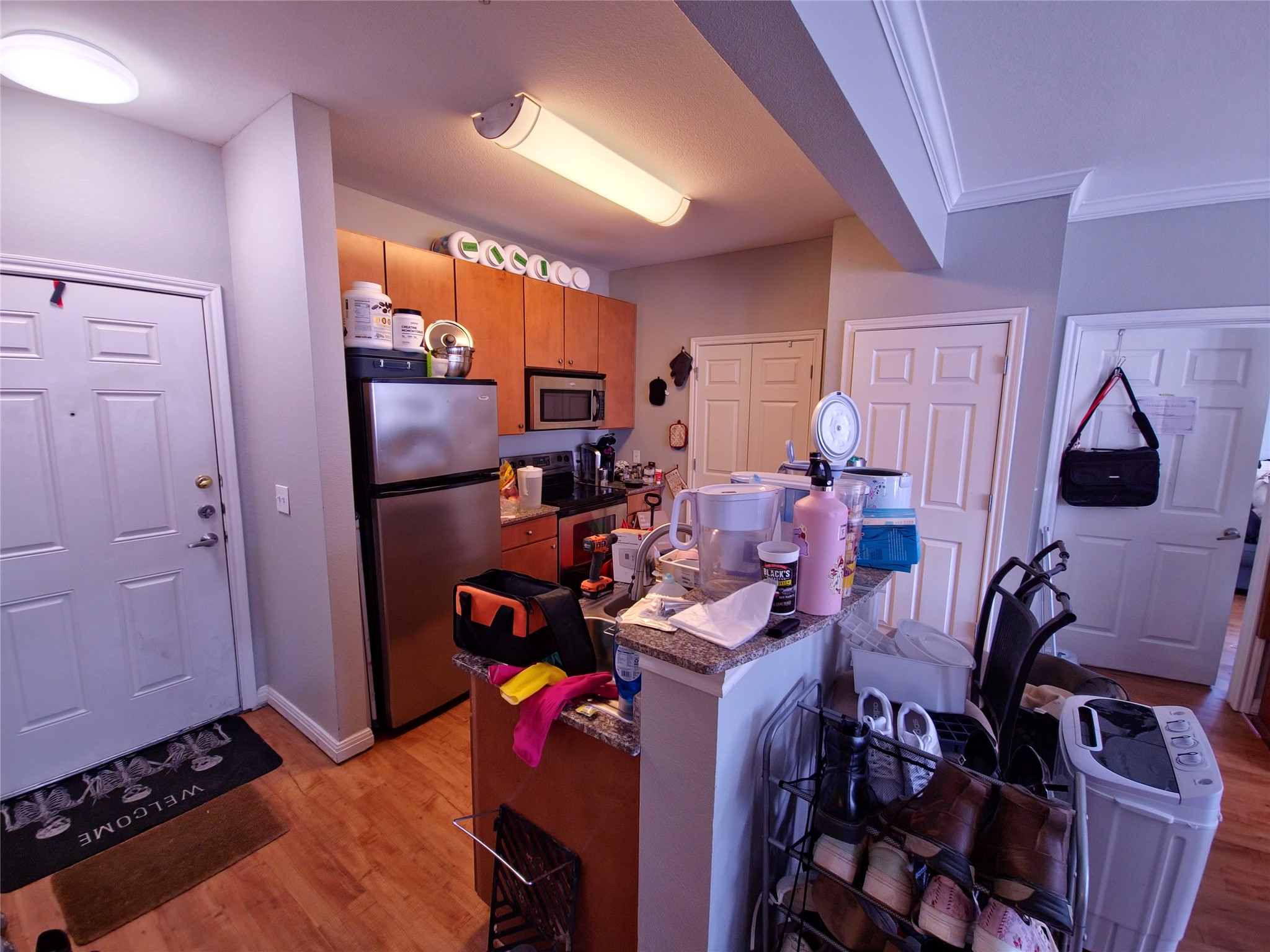 2502 Leon Street, Unit 304 Austin, TX 78705 - Photo 9 of 10 Kitchen with stainless steel appliances, light wood finished floors, a kitchen island, a kitchen breakfast bar, and crown molding