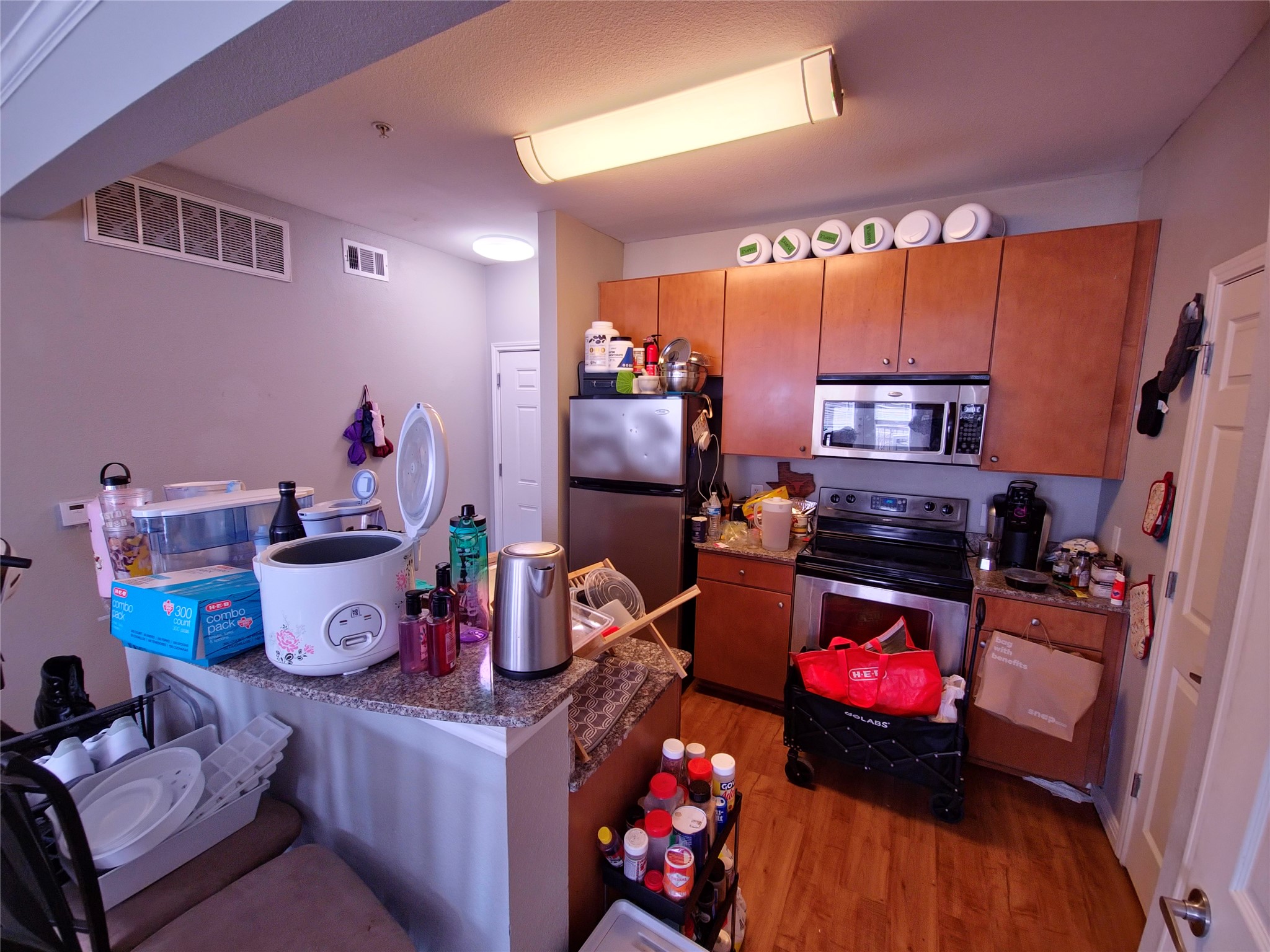 2502 Leon Street, Unit 304 Austin, TX 78705 - Photo 10 of 10 Kitchen featuring stainless steel appliances, dark wood-style flooring, dark stone countertops, and wood finish cabinetry