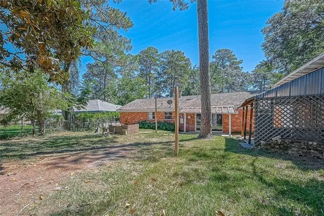 a view of a big yard with large trees and a small barn