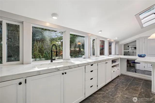 a large white kitchen with granite countertop a large window and white stainless steel appliances