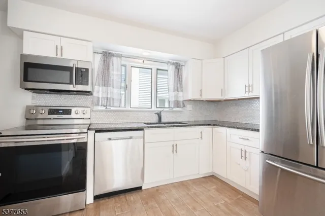 a kitchen with stainless steel appliances white cabinets a sink and a stove