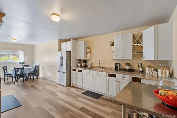 a kitchen with granite countertop a refrigerator a sink dishwasher a dining table and chairs with wooden floor