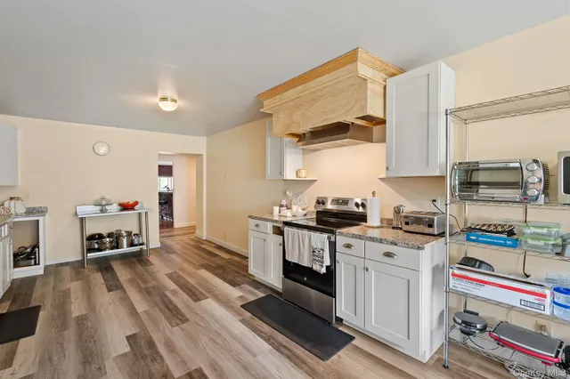 a kitchen with granite countertop a stove top oven a sink dishwasher a dining table and chairs with wooden floor