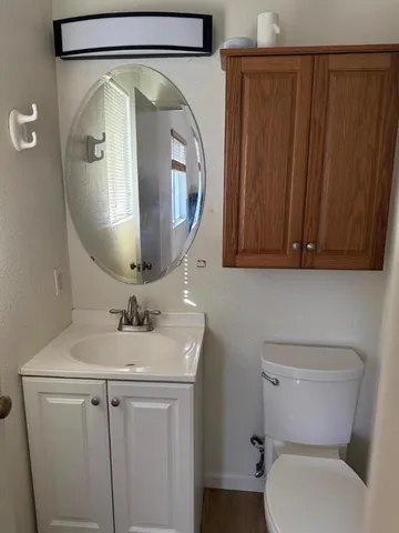 a view of a hallway with wooden floor and a bathroom