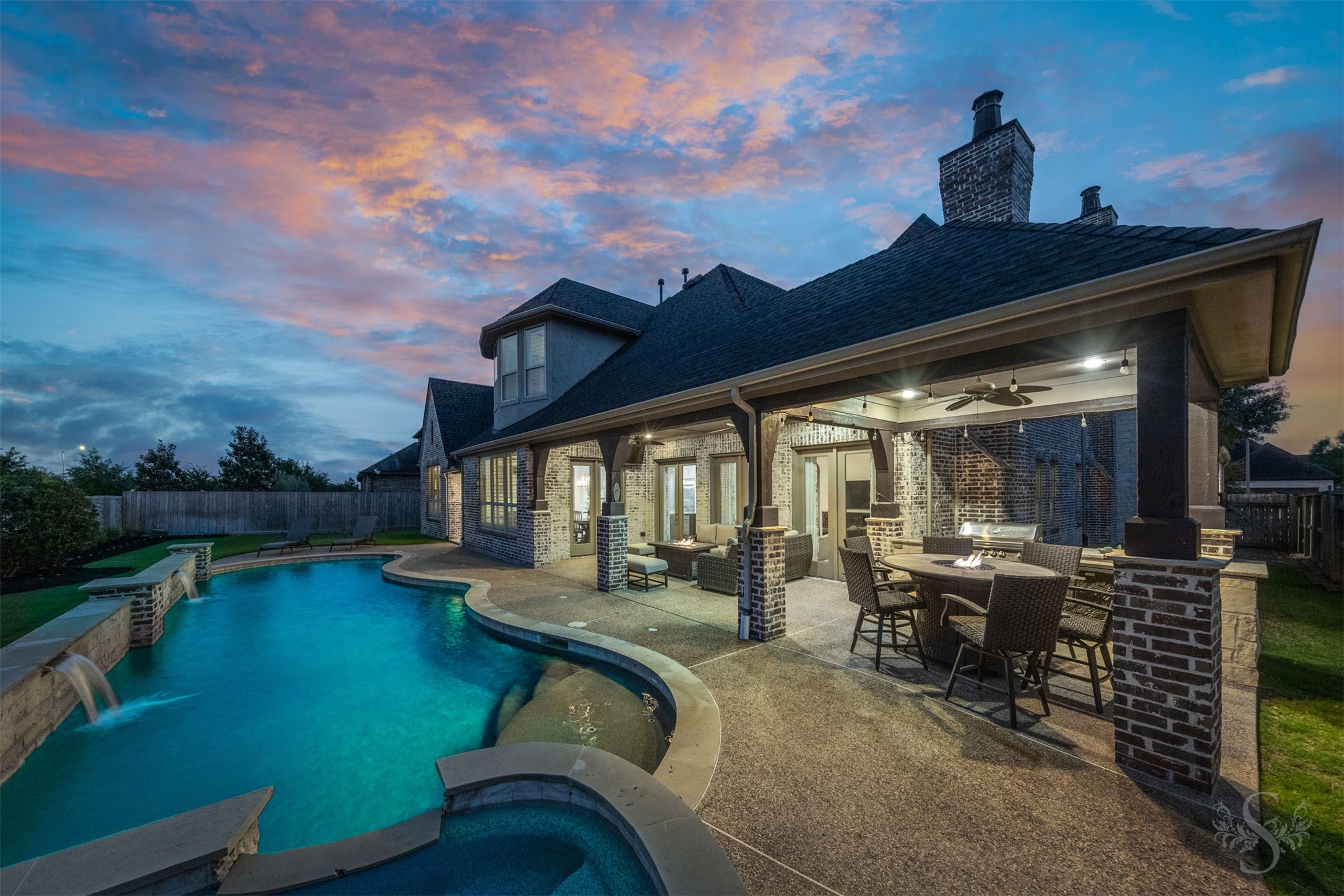 Stunning backyard retreat centers around a custom-designed pool and spa with elegant water features, expansive decking, and beautifully integrated hardscaping. The covered patio with outdoor kitchen and multiple seating areas creates a seamless indoor-outdoor experience, offering an exceptional setting for both everyday enjoyment and large-scale entertaining.