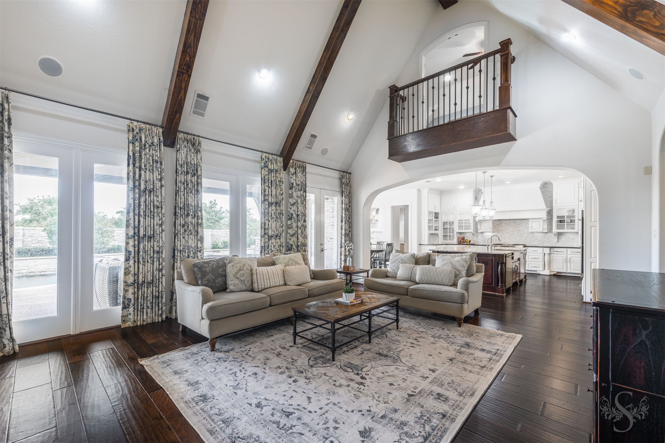 28602 Hoffman Spring Lane Fulshear, TX 77441 - Photo 2 of 49 Impressive family room showcases a soaring cathedral ceiling with wood beams, rich wood flooring, and a wall of windows offering beautiful views of the backyard retreat. Open to the kitchen, this expansive space is enhanced by the integrated stereo/Nuvo speaker system, creating the perfect setting for gatherings.