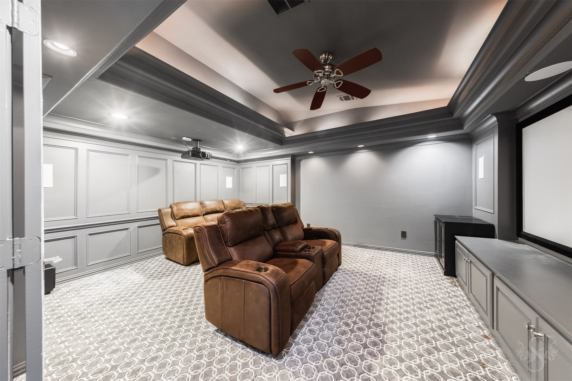 28602 Hoffman Spring Lane Fulshear, TX 77441 - Photo 26 of 49 Showstopping media room features a dramatic tray ceiling with layered detail and rich paint treatment that creates a true theater-like atmosphere. Complete with projector and screen that convey, this space is designed for an elevated movie-night experience for family and friends.