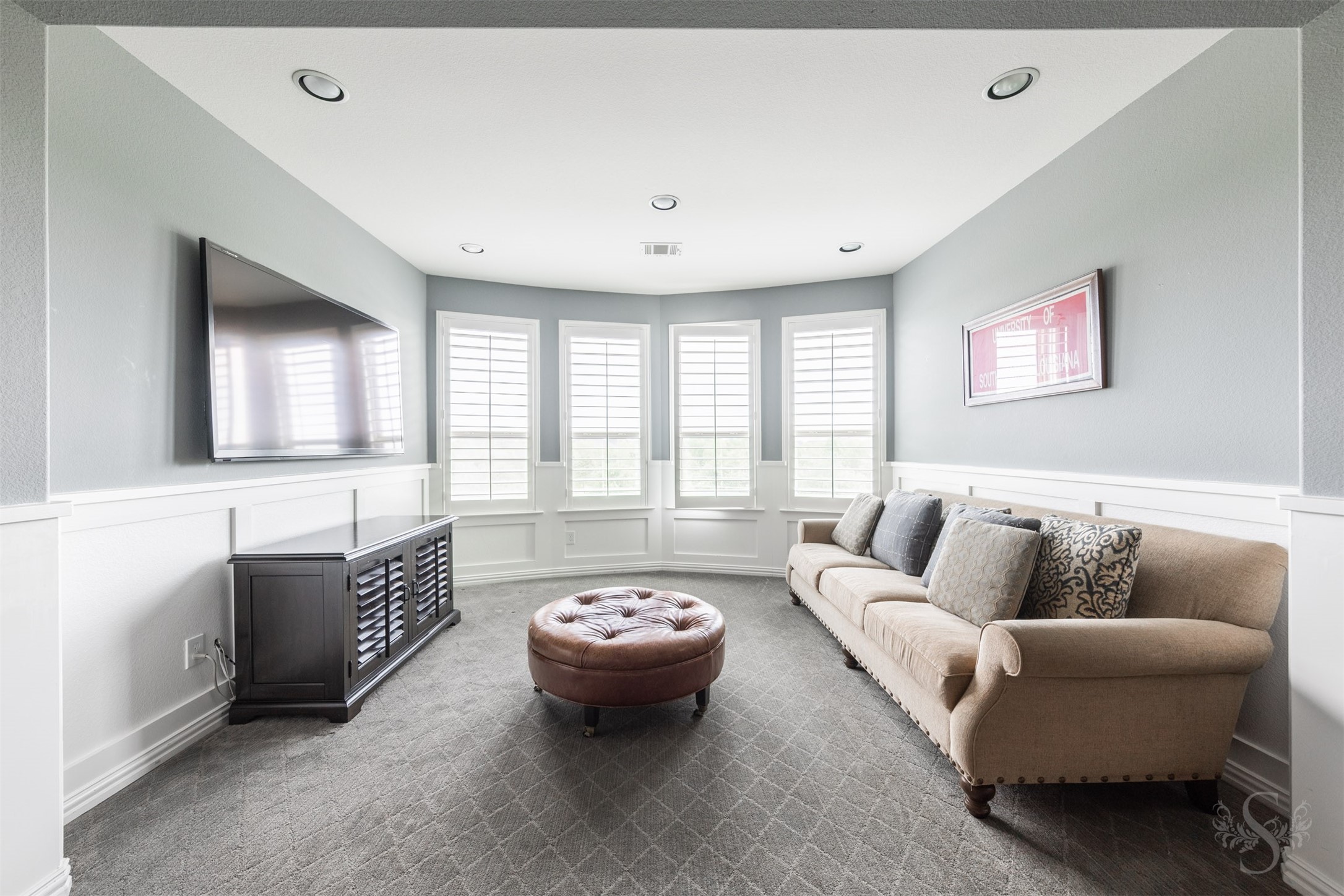 28602 Hoffman Spring Lane Fulshear, TX 77441 - Photo 28 of 49 Light-filled living area features a wall of windows with plantation shutters, creating an inviting setting for relaxed gatherings or quiet conversation. Seamlessly connected to the game room, this versatile space offers the feel of a private lounge—ideal for unwinding while remaining part of the home’s expansive entertaining level.
