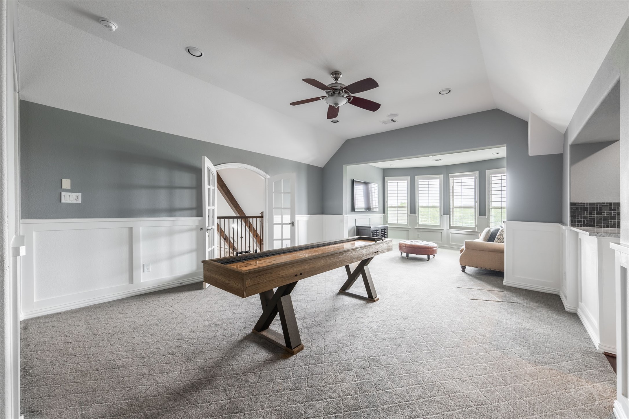 28602 Hoffman Spring Lane Fulshear, TX 77441 - Photo 29 of 49 Magnificent game room showcases custom paneled walls, elevated ceiling detail, and designer paint that adds depth and architectural interest, creating a true statement space for entertaining family and friends. Generous layout offers room for a pool table or shuffleboard, while the adjoining sitting area and built-in kitchenette with sink, cabinetry, and beverage fridge create a seamless setting for hosting on a grand scale.