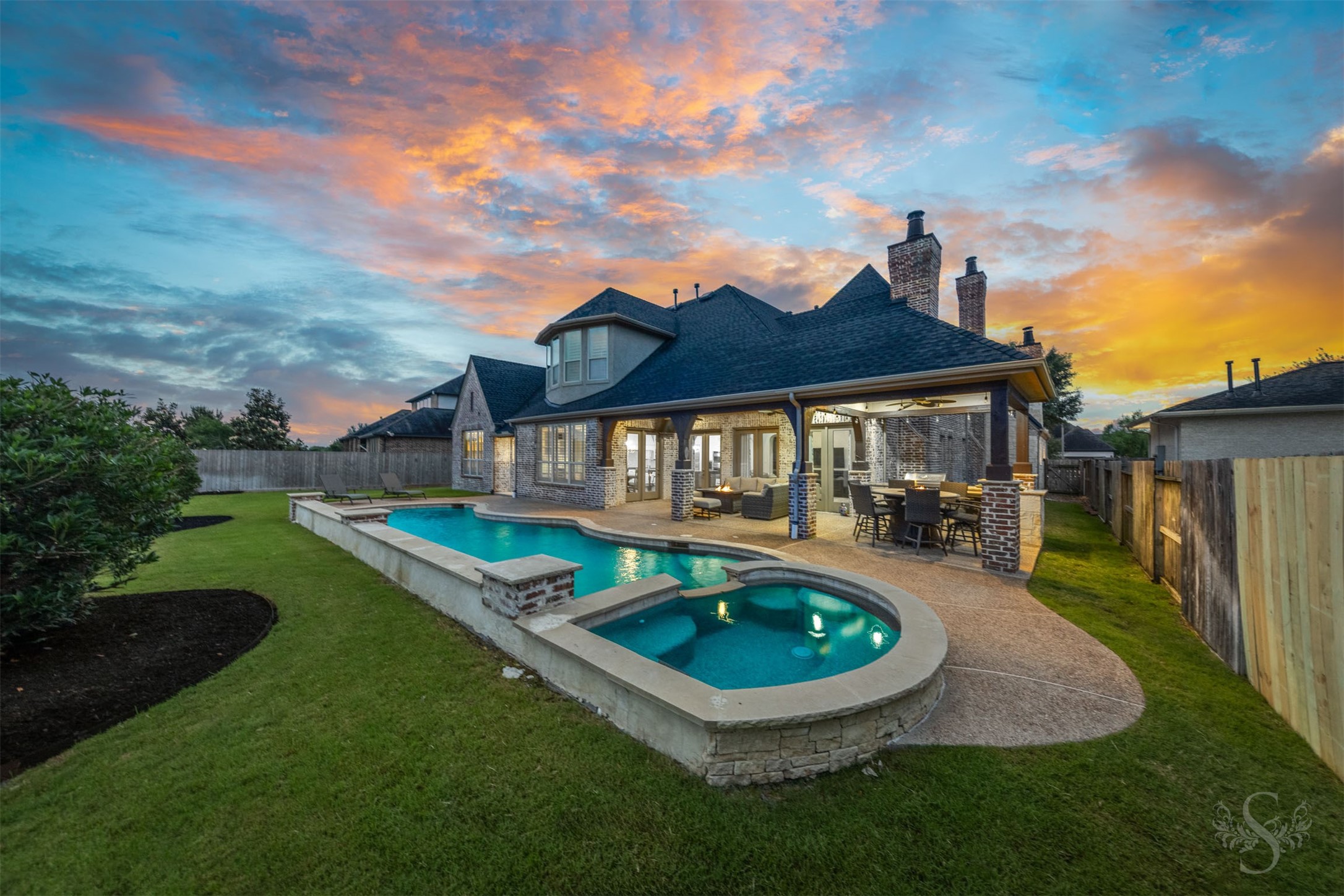 28602 Hoffman Spring Lane Fulshear, TX 77441 - Photo 38 of 49 Resort-style backyard showcases a custom pool and spa framed by expansive decking and a beautifully designed covered patio. The layout creates a seamless setting for outdoor living, with generous space for both lounging and entertaining.