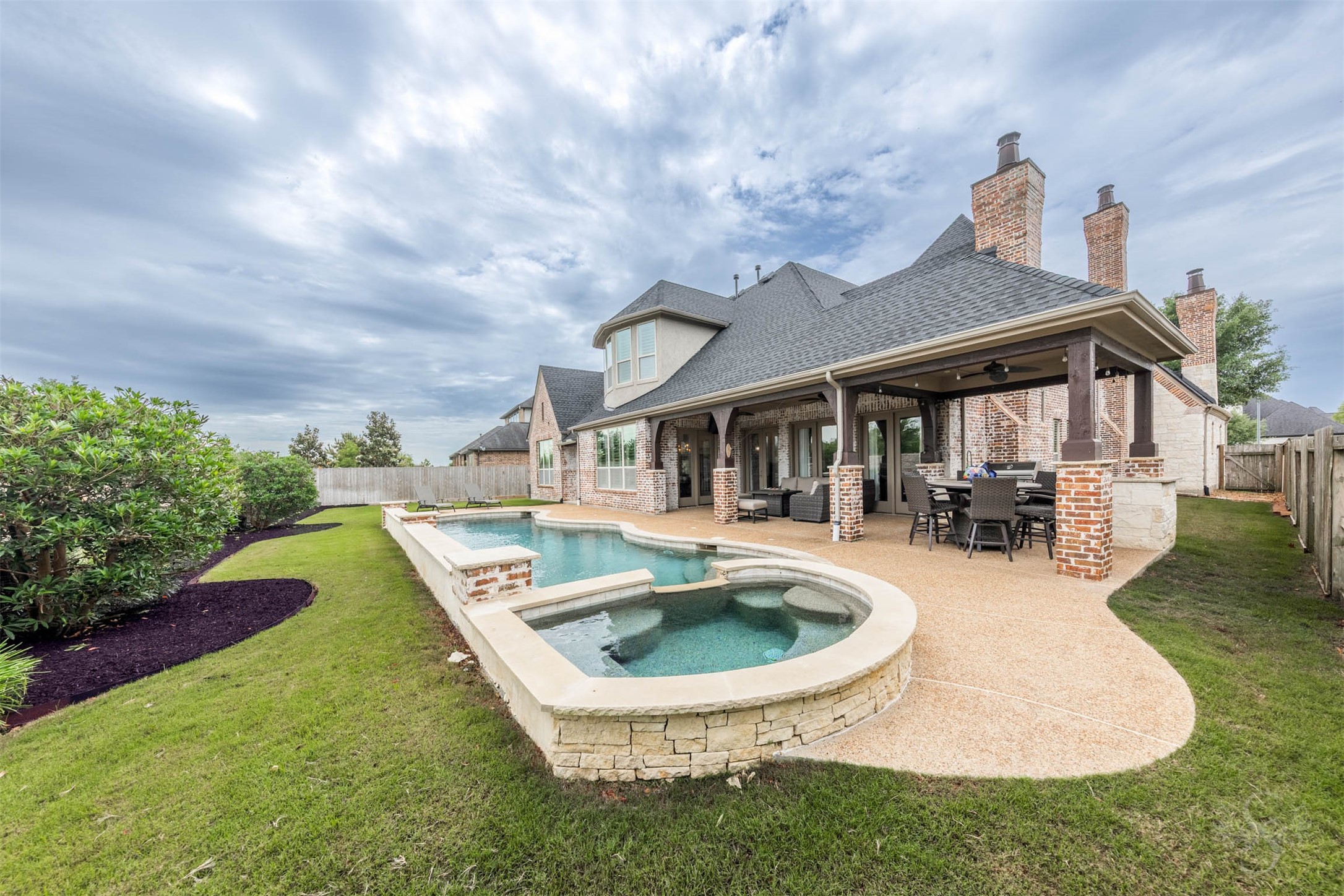 28602 Hoffman Spring Lane Fulshear, TX 77441 - Photo 41 of 49 Resort-style backyard showcases a custom pool and spa framed by expansive decking and a beautifully designed covered patio. The layout creates a seamless setting for outdoor living, with generous space for both lounging and entertaining.
