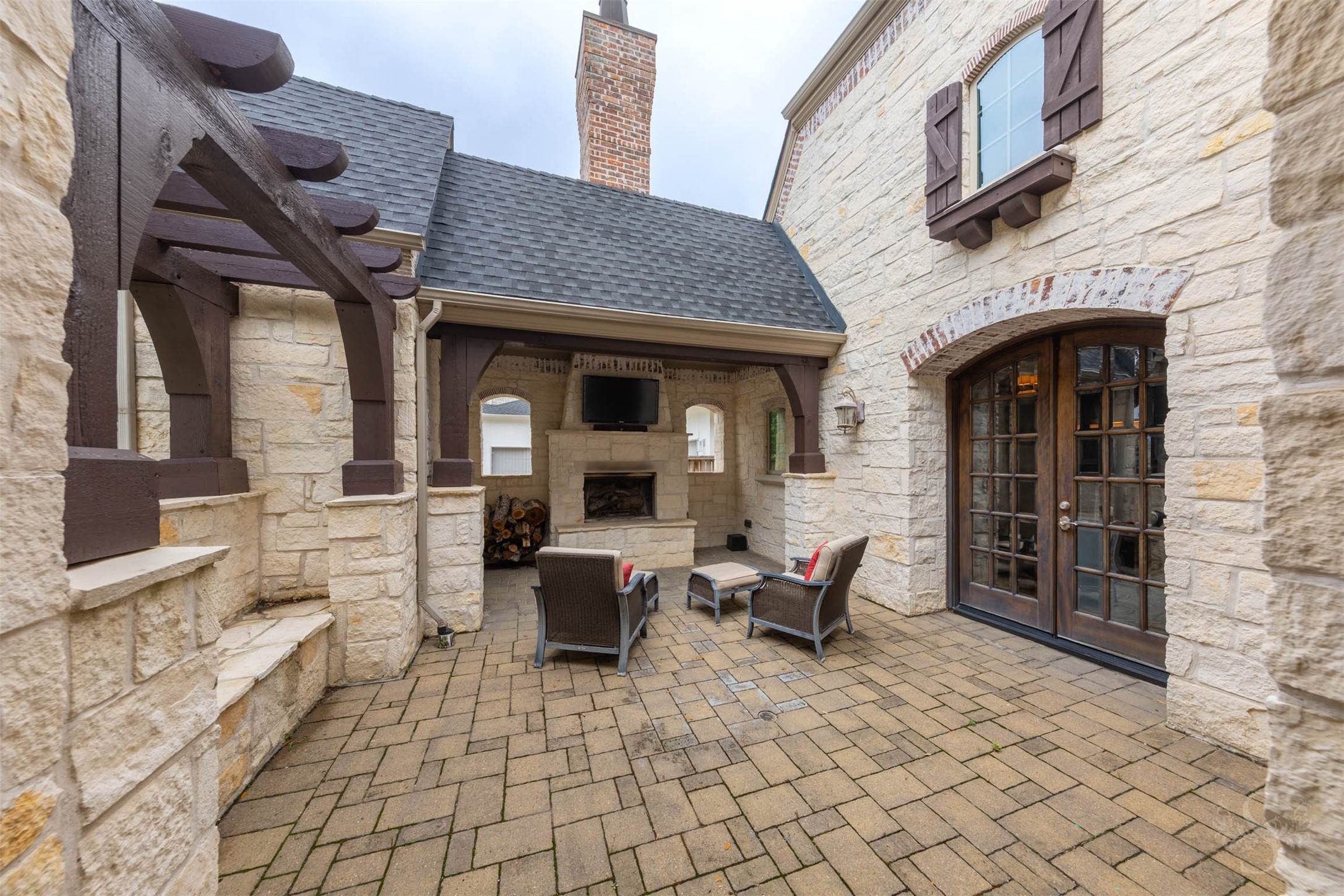 28602 Hoffman Spring Lane Fulshear, TX 77441 - Photo 44 of 49 Private front courtyard designed for year-round enjoyment, featuring a stone fireplace and covered seating area framed by arched openings and rich architectural detail. This inviting outdoor space sets the tone for the home, offering a warm welcome and an additional setting for quiet evenings or gathering with guests.
