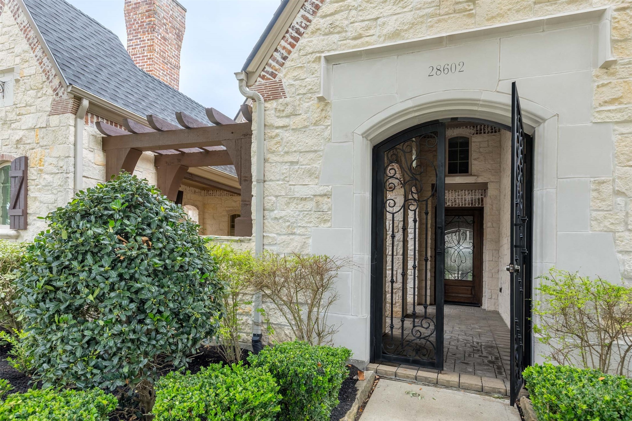 28602 Hoffman Spring Lane Fulshear, TX 77441 - Photo 45 of 49 Private gated courtyard entry creates a grand arrival experience, blending stone architecture with elegant wrought iron detailing. Covered outdoor passageways and rich architectural accents give this Huntington home a distinctive custom feel from the moment you arrive.