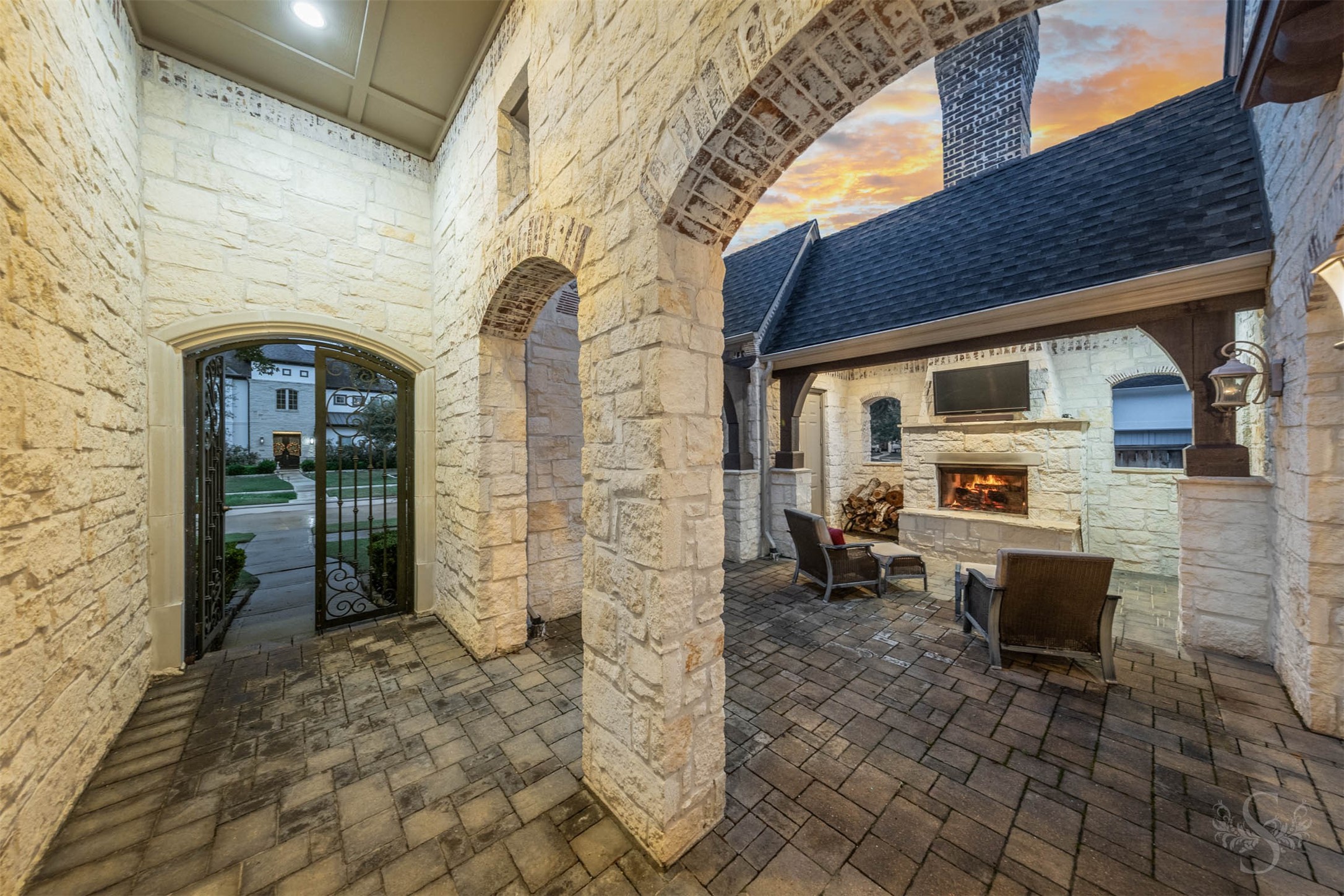 28602 Hoffman Spring Lane Fulshear, TX 77441 - Photo 6 of 49 Private front courtyard designed for year-round enjoyment, featuring a stone fireplace and covered seating area framed by arched openings and rich architectural detail. This inviting outdoor space sets the tone for the home, offering a warm welcome and an additional setting for quiet evenings or gathering with guests.