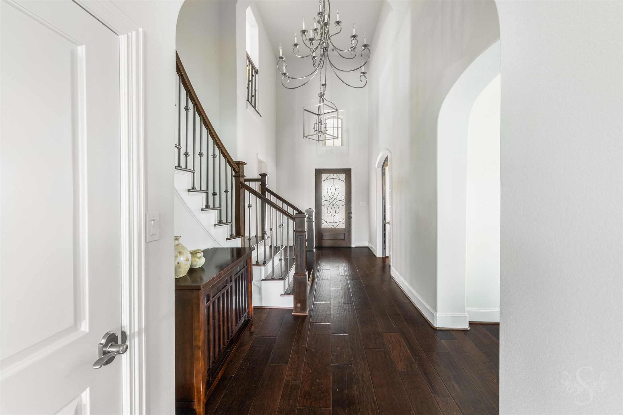 28602 Hoffman Spring Lane Fulshear, TX 77441 - Photo 7 of 49 Grand 2 story entry showcases rich wood flooring that extends throughout the main level, setting a warm, upscale tone from the moment you step inside. A sweeping staircase with iron balusters and statement lighting highlights the home’s architectural presence, creating an unforgettable first impression.