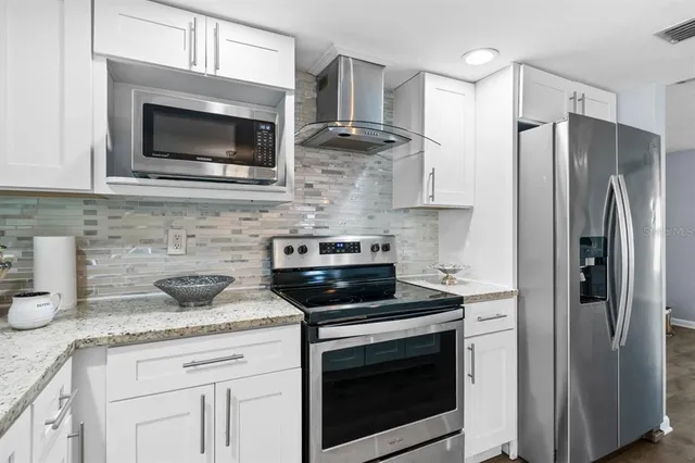 a kitchen with stainless steel appliances granite countertop a stove microwave and refrigerator