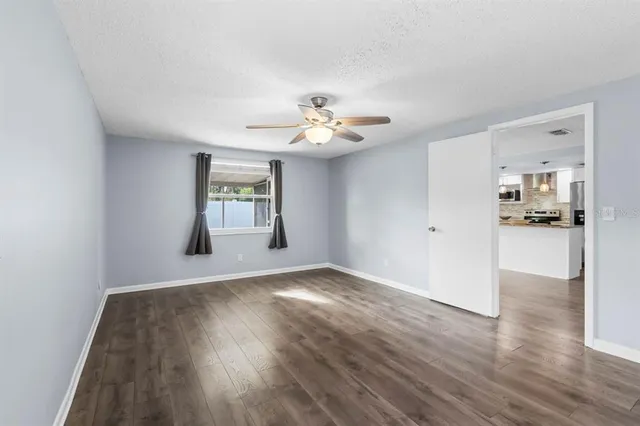 a view of an empty room with window and wooden floor