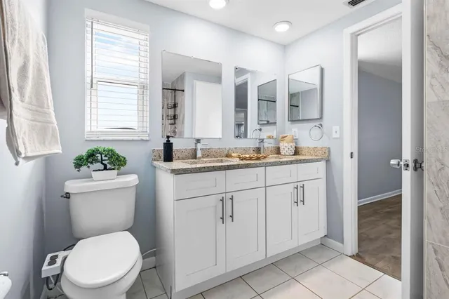 a bathroom with a granite countertop toilet sink and mirror