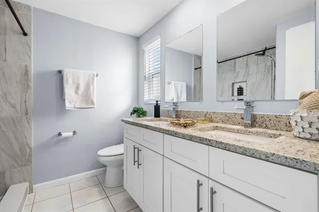 a bathroom with a granite countertop toilet sink and mirror